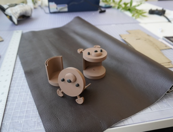 Three physical bear bracket prototypes on brown leather