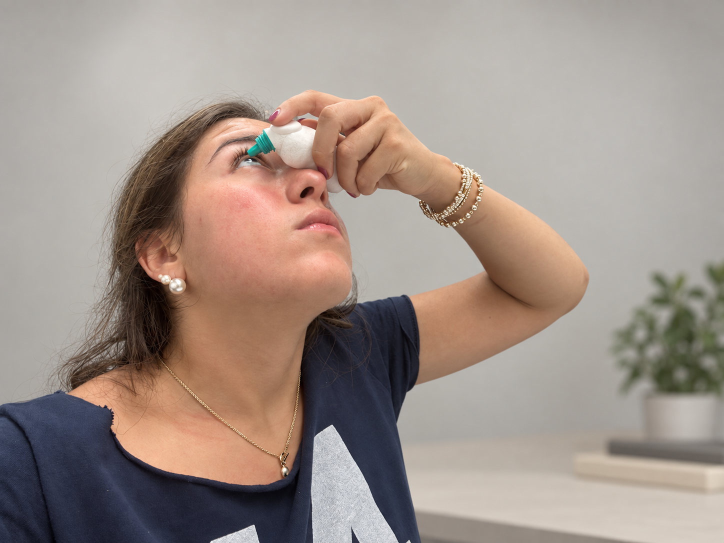 Lillian positioning a small white foam eyedrop dispenser model with a teal nozzle above her eye